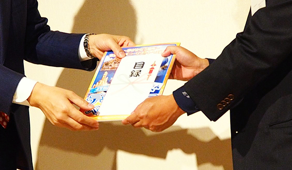 写真：代表取締役　加藤(左)より目録の贈呈